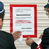 神戸山口組が特定抗争指定暴力団となり、大阪府警の捜査員が組事務所の入り口に出入り禁止の標章を張り付ける＝2020年1月7日午前、大阪市中央区 　写真提供：産経新聞社 