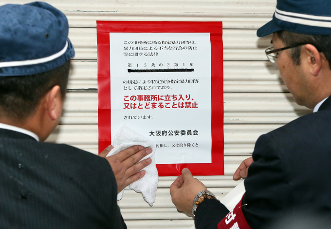 神戸山口組が特定抗争指定暴力団となり、大阪府警の捜査員が組事務所の入り口に出入り禁止の標章を張り付ける＝2020年1月7日午前、大阪市中央区 　写真提供：産経新聞社