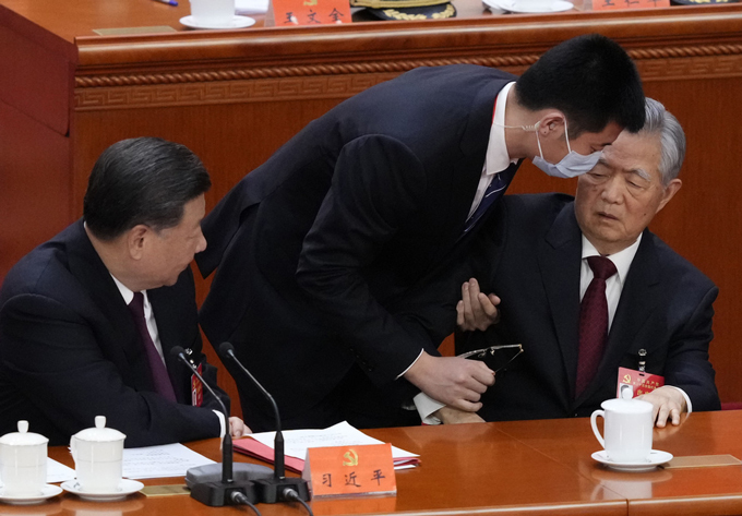 第20回中国共産党大会の閉幕式で、退席する胡錦濤前総書記（右）。左は習近平総書記＝2022年10月22日、北京の人民大会堂（共同）