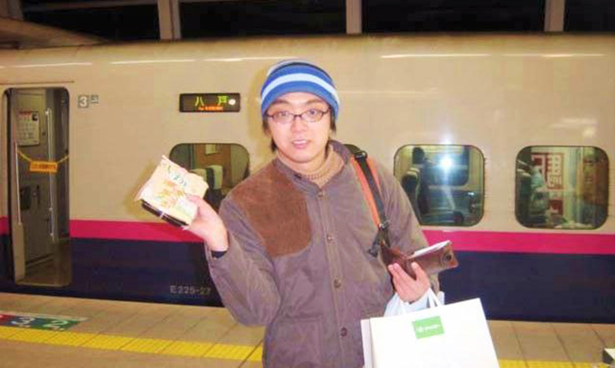 吉田屋の「いわし蒲焼き弁当」（現在は販売終了）を片手に、E2系新幹線電車「はやて」の発車を待つ筆者（2003年撮影）