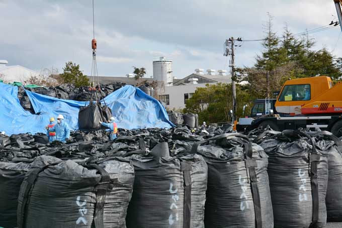 除染廃棄物が入った黒い袋が積み上げられた中間貯蔵施設予定地内の保管場。大型トラックがひっきりなしに出入りし、クレーンがうなりを上げていた=2016年02月24日、福島県大熊町　写真提供：産経新聞社