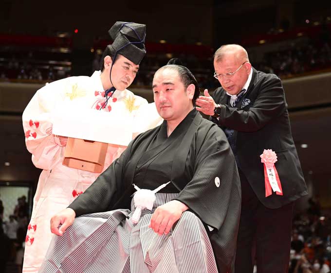 大相撲　元関脇安美錦引退・安治川親方襲名披露大相撲　断髪式で落語家・笑福亭鶴瓶（右）にはさみを入れてもらう、元安美錦の安治川親方。行司は木村寿之介　＝2022年05月29日、東京・両国国技館　（代表撮影）写真提供：産経新聞社