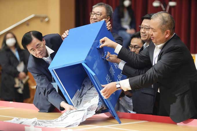 投票箱を開ける香港政府トップの李家超行政長官（右から2人目）＝2023年12月11日、香港（共同）