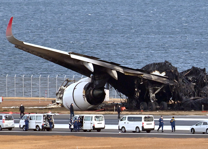 C滑走路脇に横たわる日航機の残骸の前では現場検証が行われている＝2024年1月4日午前9時31分、羽田空港（酒巻俊介撮影）　写真提供：産経新聞社