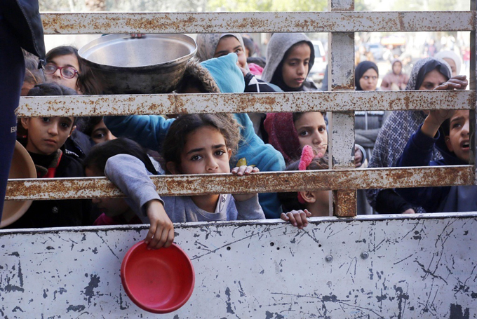 パレスチナ自治区ガザ中部デールバラハで食料の配給を待つ子どもら（ゲッティ＝共同）2024年1月28日