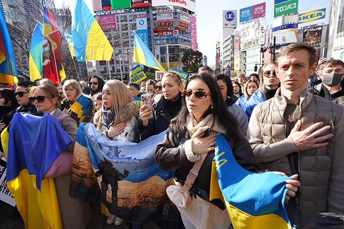 【ウクライナ侵略2年】JR渋谷駅前でロシアに対し抗議活動をする在日ウクライナ人ら。ウクライナの国歌を聞く人たち＝2024年2月24日午後、東京都渋谷区（鴨川一也撮影）　写真提供：産経新聞社