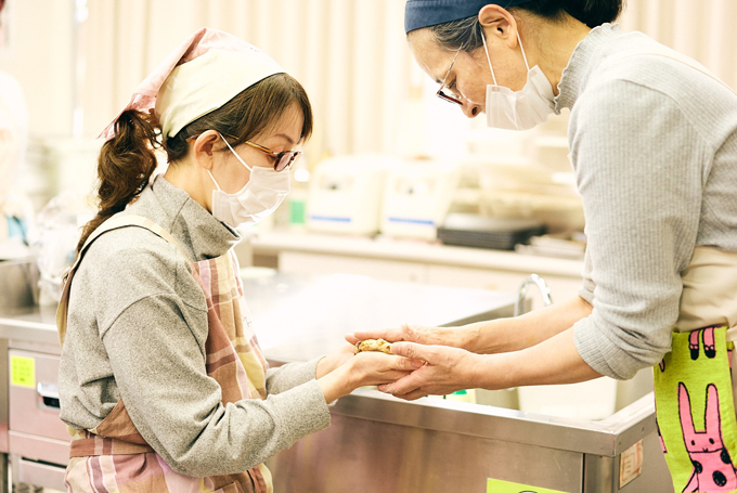 感触を伝えるために参加者の手に生地を乗せる兼重氏